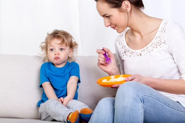 Mutter füttert Kind auf Sofa — Stockfoto