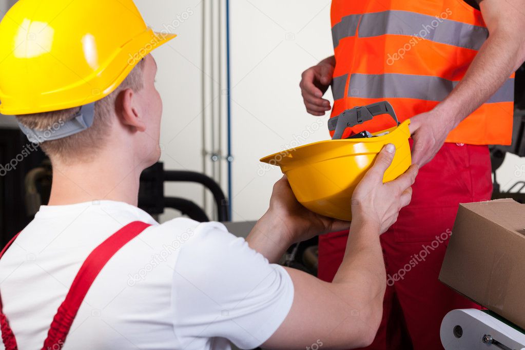 Worker giving colleague hardhat