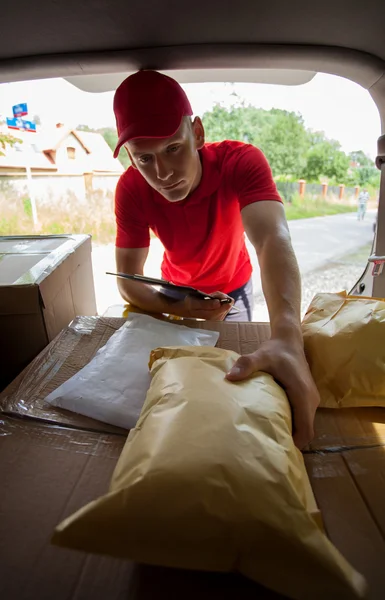 Courrier prenant colis du coffre de la voiture — Photo