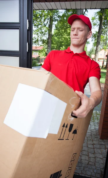 Delivery man holding a heavy box — Stock Photo, Image