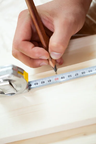 Man's hands measuring board's length — Stock Photo, Image