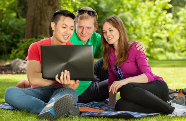 Friends sitting on blanket in park — Stock Photo, Image
