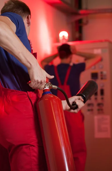 Hombre usando extintor de incendios en fábrica — Foto de Stock