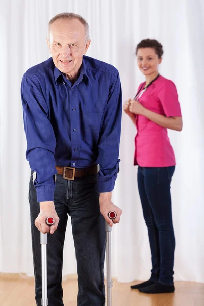 Physiotherapist and  man walking with crutches — Stock Photo, Image