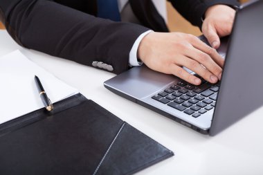 Eller dizüstü bilgisayarda yazıyor.