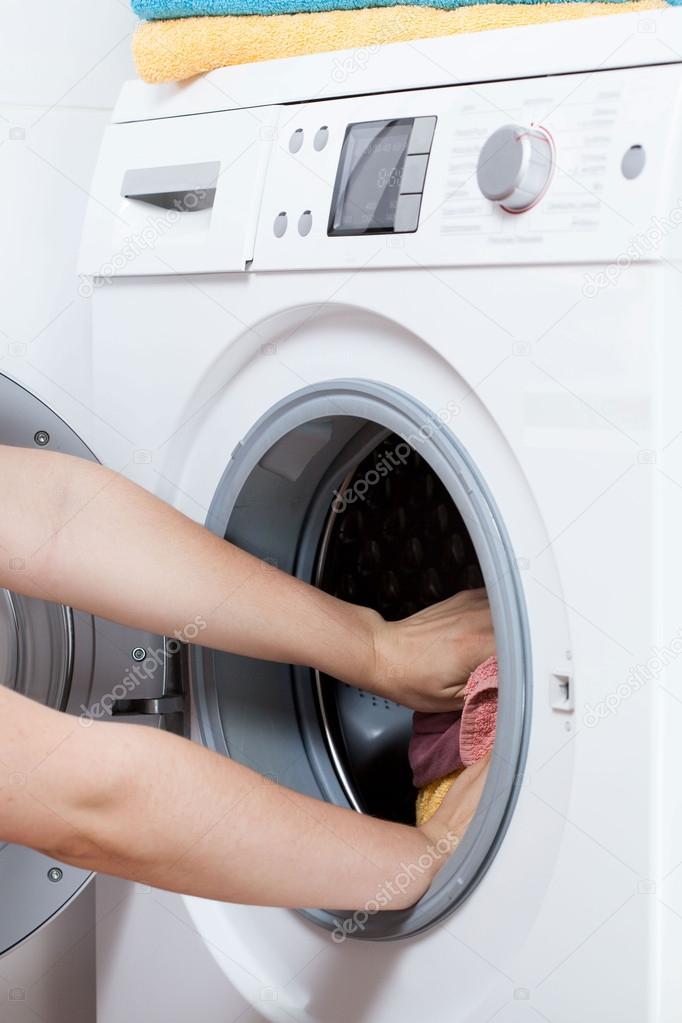 Hands putting laundry into washing machine