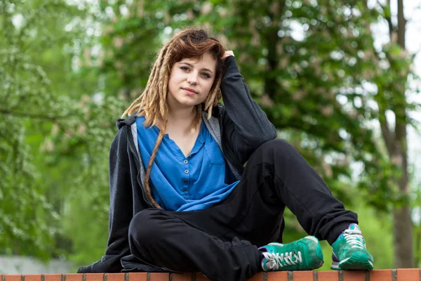 Flicka sitter på tegelvägg — Stockfoto