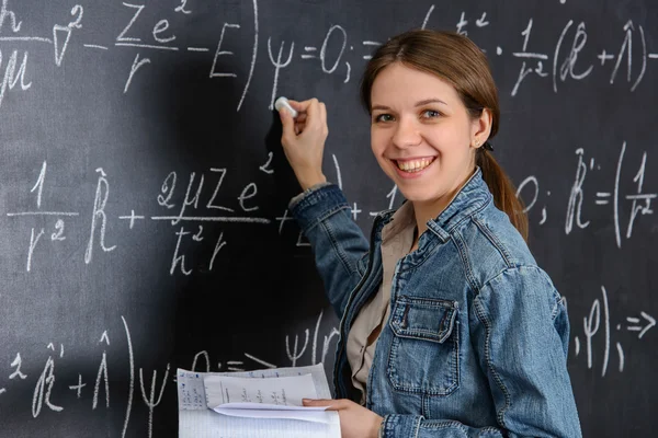 Ritratto di una bella studentessa che fa matematica su una lavagna — Foto Stock