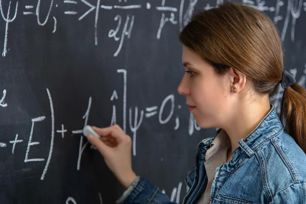 Ritratto di una bella studentessa che fa matematica su una lavagna — Foto Stock