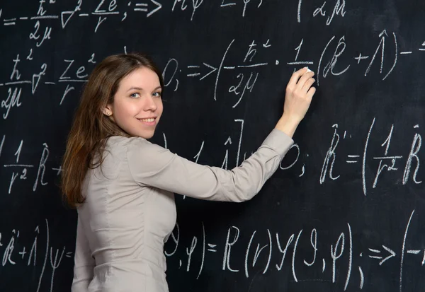 Портрет красивой студентки, занимающейся математикой на доске — стоковое фото