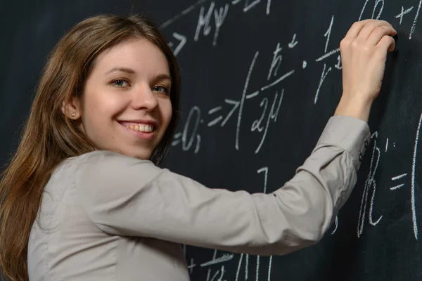 Портрет гарненького студента, що робить математику на дошці Стокове Фото