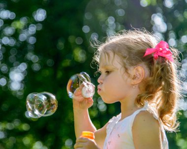 Küçük kız sabun köpüğü üflüyor