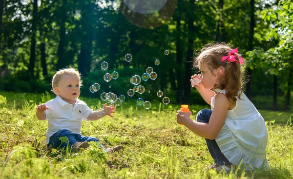 Kız ve oğlan sabun köpüğü ile oynama — Stok fotoğraf