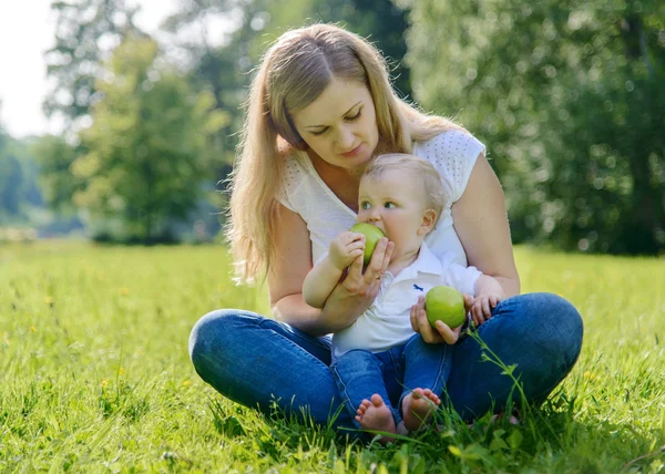 Happy family sitting on grass in park — Stock Photo, Image