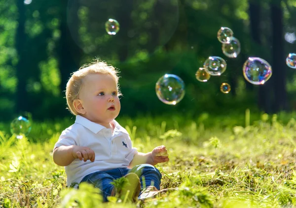 Küçük çocuk sabun köpüğüyle oynuyor.