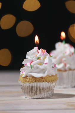 Tahta masanın üzerinde doğum günü pastaları ve ışıklar..