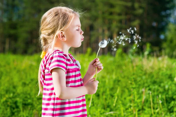 Adorabile bionda bambina che soffia un dente di leone — Foto Stock