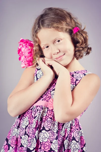 Menina bonita com uma flor rosa em seu cabelo — Fotografia de Stock