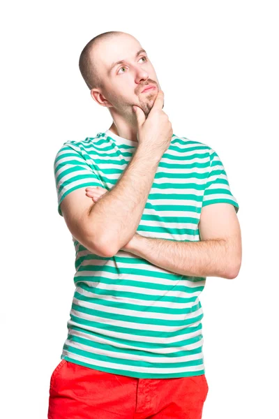 Σκέψη νεαρός άνδρας με ριγέ άσπρο και το τιρκουάζ t-shirt και πορτοκαλί τζιν απομονωθεί σε λευκό — Φωτογραφία Αρχείου