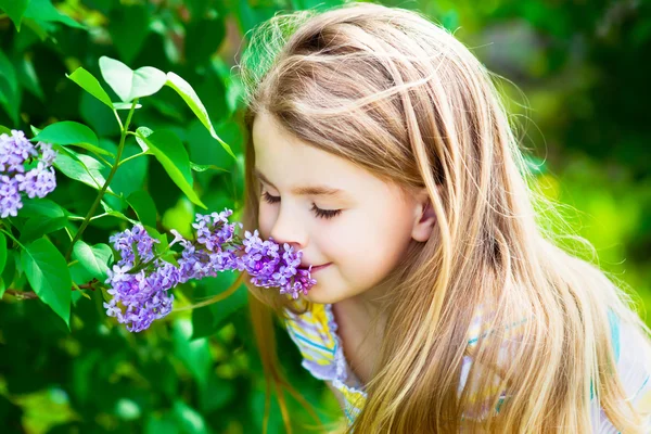 Menina loira bonita com cabelo comprido cheirando flor — Fotografia de Stock