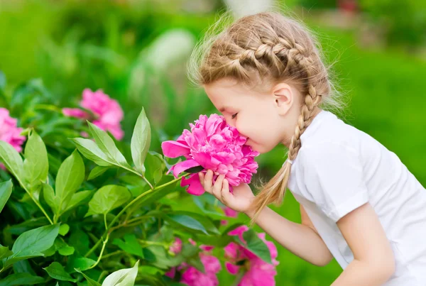 Beautiful blond little girl with long hair smelling flower — Stock Photo, Image