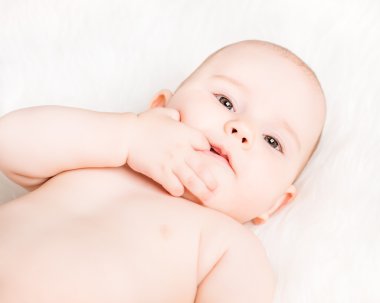 portre portre sevimli gülümseyen bebek beyaz kürkü yalan ve parmak emme