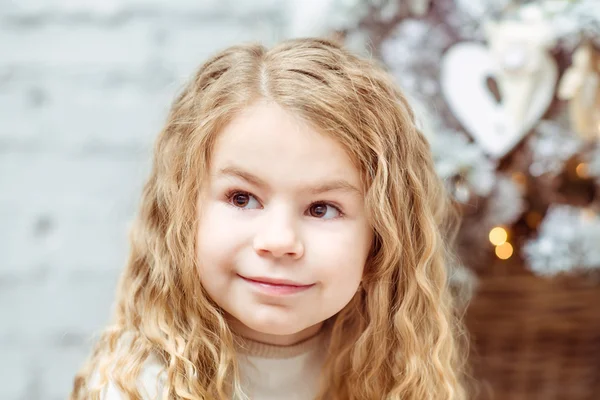 Adorable blond little girl sitting under the Christmas tree and dreaming, closeup portrait — Stock Photo, Image