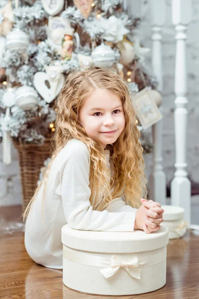 Vacker blond liten flicka sitter under granen med presentask — Stockfoto