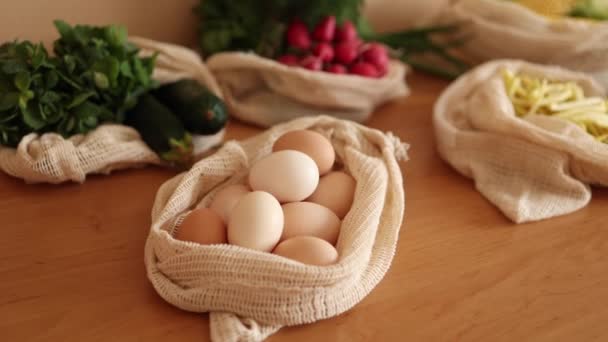 Bakkal çantasındaki yumurtalar. Eko çiftliğinden yumurtalar. Tahta masadaki pamuk torbaları. Sıfır atık alışveriş kavramı. Plastiksiz ögeler — Stok video