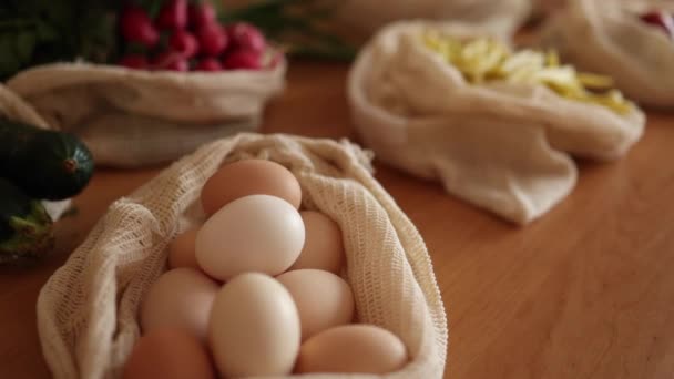 Αυγά σε τσάντα παντοπωλείου. Αυγά από οικολογική φάρμα. Βαμβακερές σακούλες σε ξύλινο τραπέζι. Καμία ιδέα για ψώνια αποβλήτων. Πλαστικά είδη — Αρχείο Βίντεο
