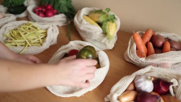 女手从帆布购物袋中取出西红柿.在木制桌子上可重复使用的生态棉袋中的蔬菜。零浪费购物的概念。无塑胶制品 — 图库视频影像