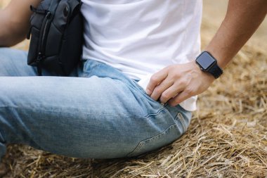 Bir adam samanlıkta oturur ve cebinden telefonu alır.