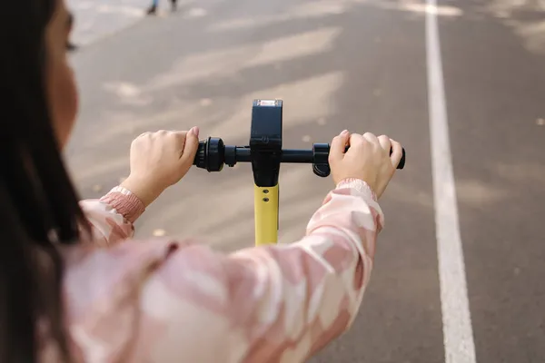 Jovem montando uma scooter elétrica em uma reunião. Conceito de transporte ecológico. Atraente feminino ao ar livre com e-scooter — Fotografia de Stock