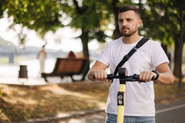 Toplantıda elektrikli scooter kullanan genç bir adam. Ekolojik ulaşım konsepti. E-scooterlı yakışıklı bir adam.