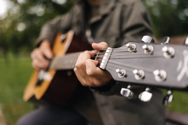 Close-up van een tiener die gitaar speelt. Mannelijke vinger op snaren die een akkoord maken. Herfst stemming buiten — Stockfoto
