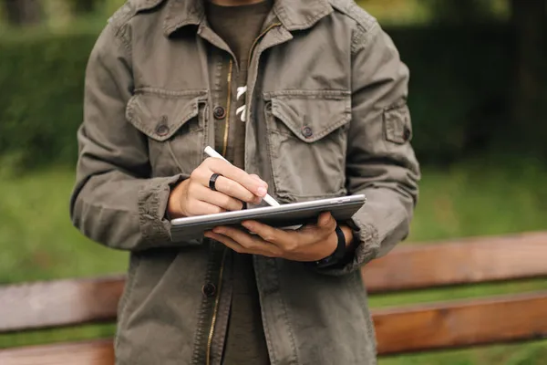 Primer plano de la pintura de niño en la tableta con lápiz. Diseñador joven usando tableta al aire libre. Selección intermedia. Tiempo de otoño —  Fotos de Stock