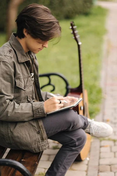 Εφηβική ζωγραφική στο δισκίο χρησιμοποιώντας μολύβι. Νεαρός σχεδιαστής με tablet εξωτερική. Πλευρική άποψη. Φθινόπωρο — Φωτογραφία Αρχείου