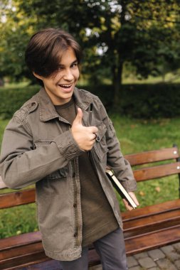 Mutlu gülümseyen genç başparmaklar yukarı ve göz kırp, göz kırp