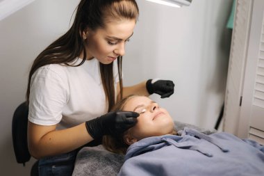 Genç bir kadın güzellik salonunda kirpik yapmak için burnunu sokuyor.