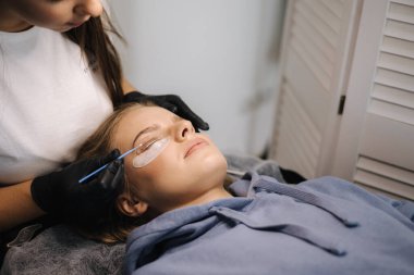 Güzellik stüdyosunda kirpik kaplama yaptıran çekici sarı saç modeli. Kırbaçlar için modern kullanışlı işlem