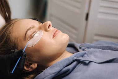 Güzellik stüdyosunda kirpik kaplama yaptıran çekici sarı saç modeli. Kırbaçlar için modern kullanışlı işlem