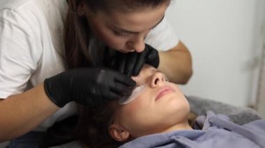 Genç manken için kirpik kaplama prosedürleri yapan bir güzellik uzmanı. Modern kirpik bakım prosedürleri laminasyon ve kirpiklerin genişletilmesi. Profesyonel güzellik salonu.