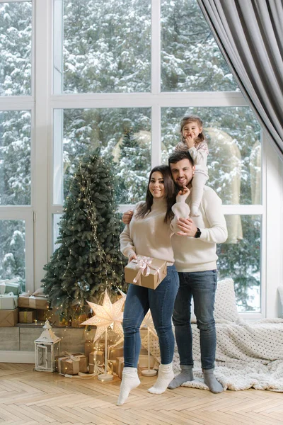 Чарівна маленька дівчинка з мамою і татом розважається на Різдво. Стильна сім'я вдома — стокове фото