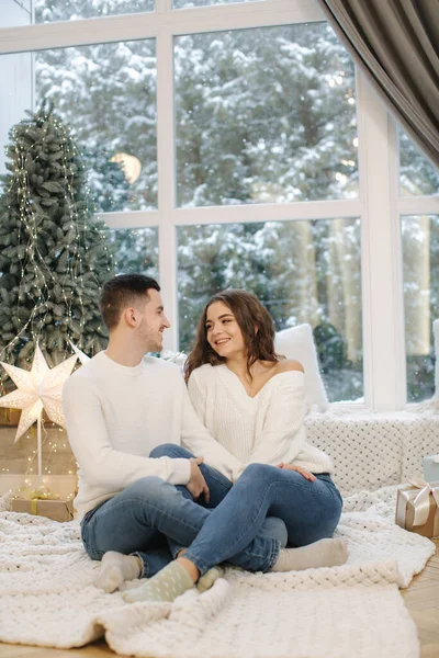 Menino bonito com sua bela namorada abraçar uns aos outros em casa na véspera de Natal. Árvore de ajuste e neve forasteiro. Humor de Natal — Fotografia de Stock