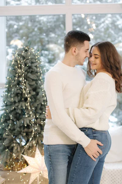 Hermosa pareja joven posando para el fotógrafo en el estudio de Año Nuevo. Árbol de Navidad. Nieve afuera — Foto de Stock