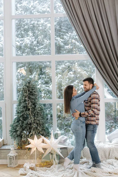 Um homem bonito com os seus cinco lindos em frente à grande janela. Neve lá fora. Árvore de abeto e muitos presentes para cauda de fada de Natal — Fotografia de Stock