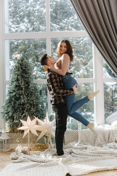 Bonito homem com sua namorada desfrutando de tempo nevado fora e se divertir perto de abeto em casa. — Fotografia de Stock
