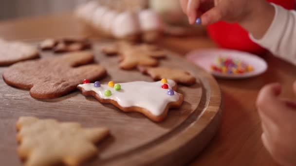 Close-up of little girl decorates gingerbread using multicolored beads. Christmas and New Year traditions concept. Christmas mood. Happy hollidays — 图库视频影像