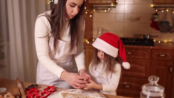 Teen piparkakkua kotona. Pikkutyttö, jonka äiti leikkaa piparkakkutaikinaa. Joulun ja uudenvuoden perinteet käsite. Joululeipomo. Hyvää joulua. — kuvapankkivideo