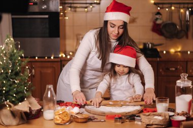 Anne ve kızı zencefilli ekmek yapmak için merdane kullanıyorlar. Zencefilli ekmek için hamurun en iyi görüntüsü. Noel havası. Tatil hazırlığı